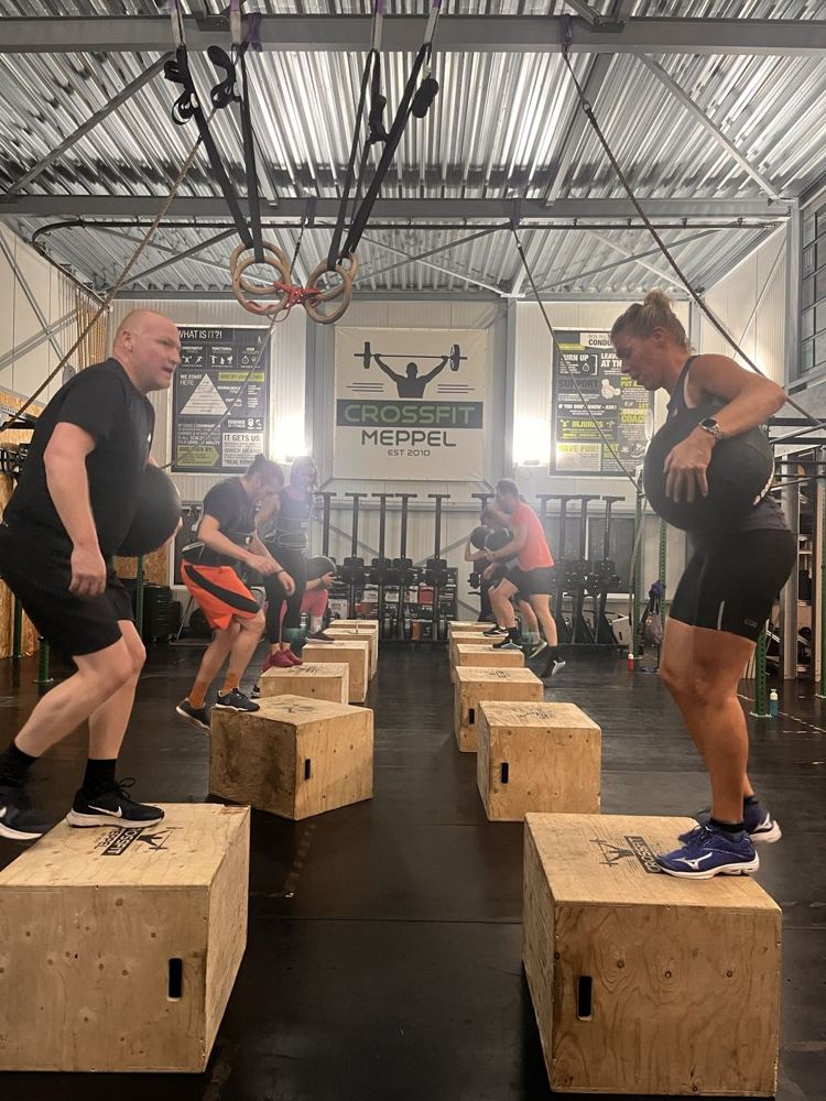Leden doen step-ups met een medicine ball in de zaal van CrossFit Meppel
