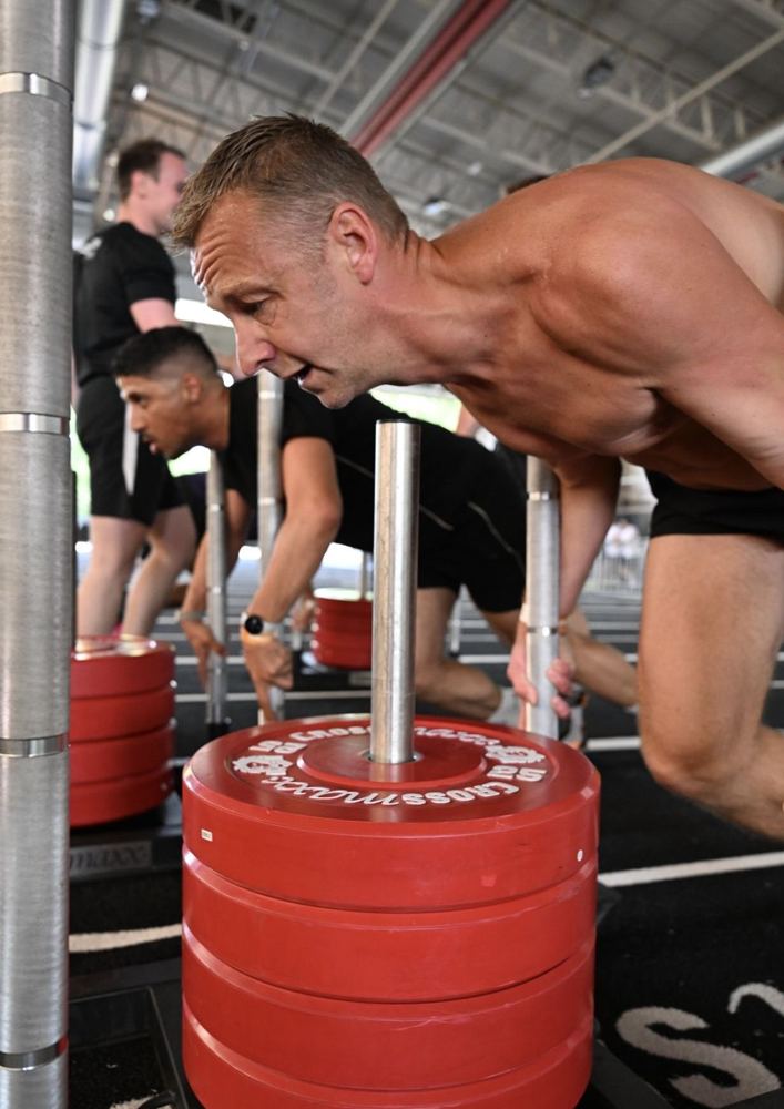 Een lid duwt een sled tijdens een Gymrace